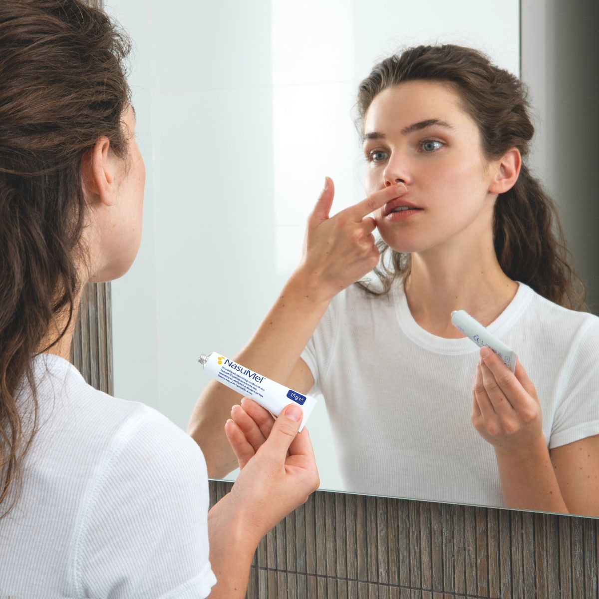 A young women applying NasuMel honey nasal ointment